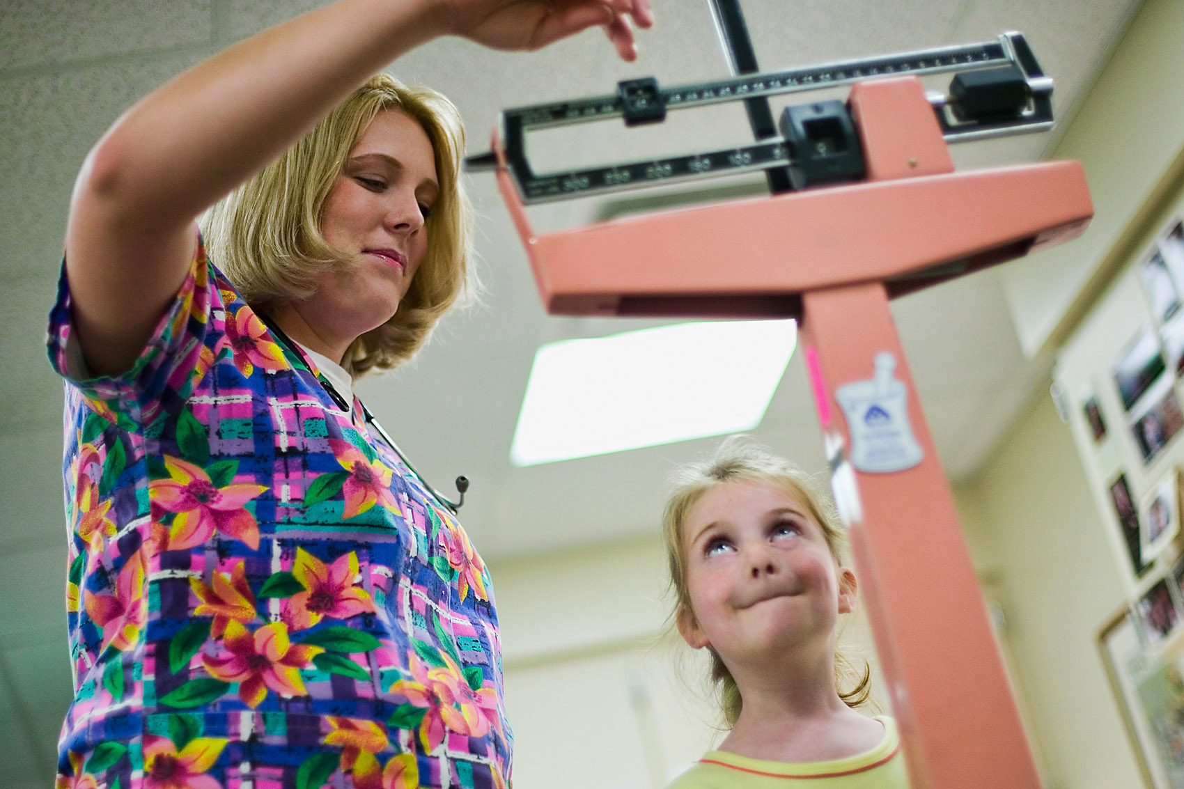 Nurse RN weighs a cute little girl on a scale.